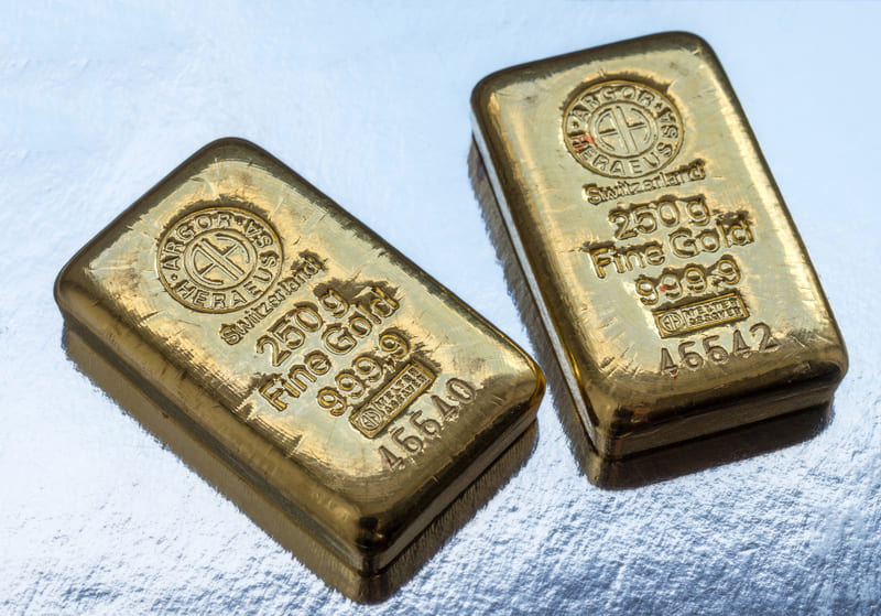 Image of two cast Argor- Heraeus gold bars against a silvery background