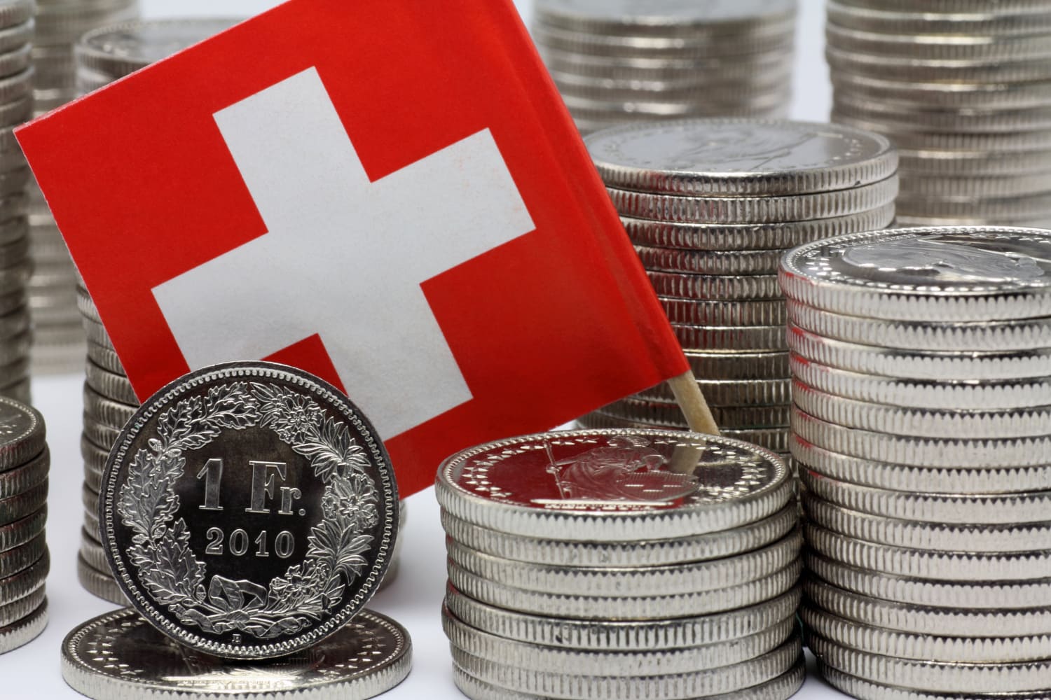 A stack of Switzerland coins and a Switzerland flag.